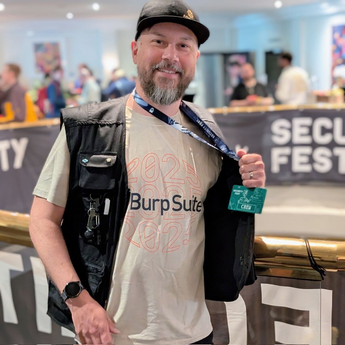 A Security Fest crew member proudly showing his Burp Suite 2025 t-shirt and Security Fest crew badge