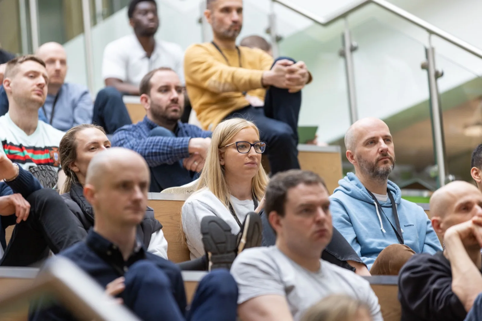 Crowd at Friday All Hands, a blond-haired woman in focus listening intently