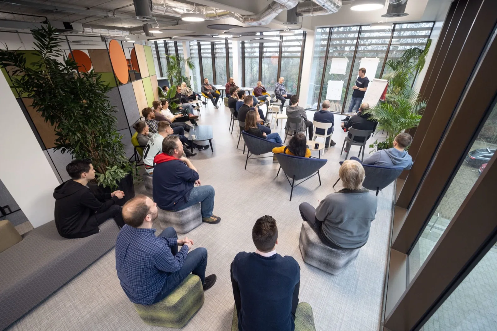 A group of around twenty Swiggers gathered in the office, one person leading an exercise at a flip chart
